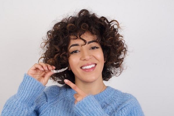 Woman smiling and pointing at her Invisalign aligners