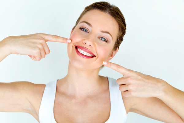 Woman smiling and pointing at her beautiful teeth