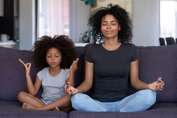 Mother and daughter sitting on the couch and meditating