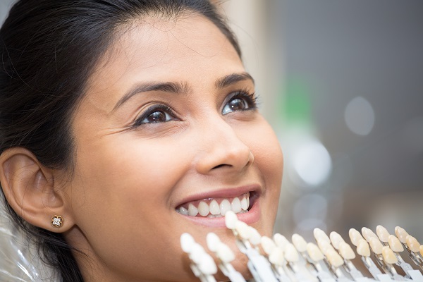 Woman being shown various shade of dental veneers