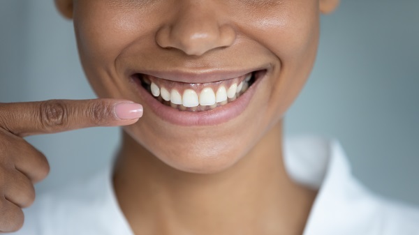 Woman smiling and pointing at perfect teeth